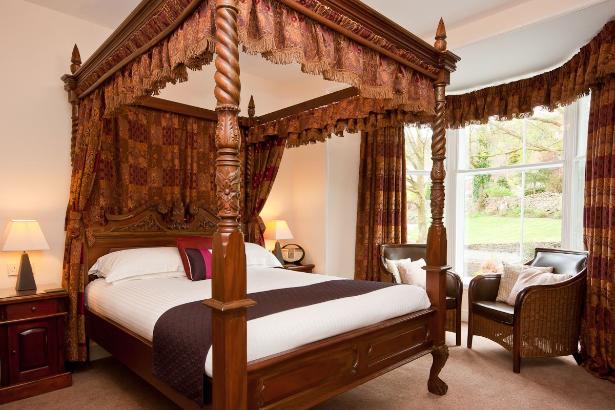 Four-poster double room with a dark wood four-poster bed in daylight